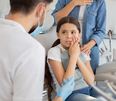 Child with toothache talking to pediatric dentist