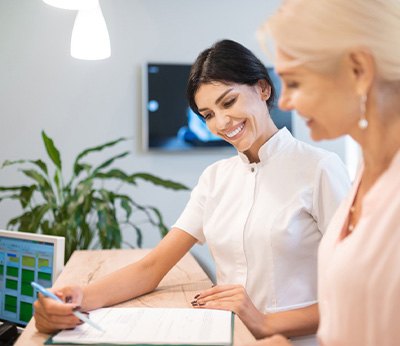 Smiling dental assistant showing patient forms