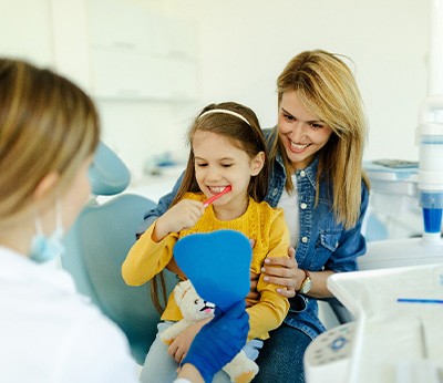 Child sitting on mom's lap while brushing teeth