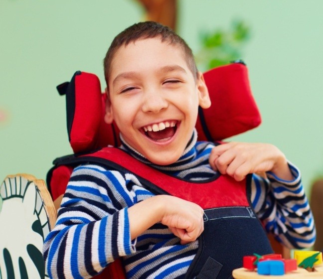 Laughing child in wheelchair after special needs dentistry