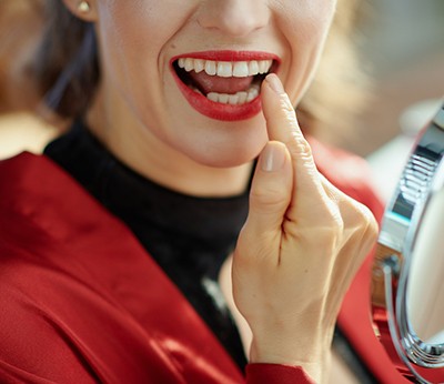Woman checking her smile in a small mirror