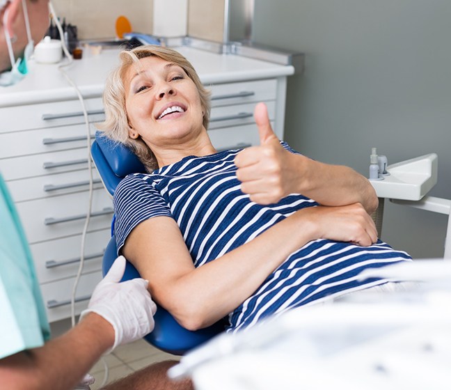 Woman in dental chair giving thumb up