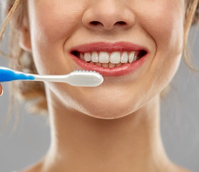 young woman smiling while brushing teeth