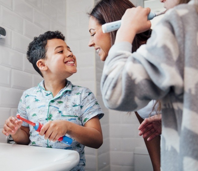 Mother and children brushing teeth to prevent dental emergencies