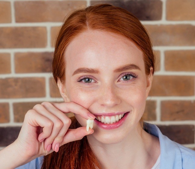 Woman holding up an extracted tooth