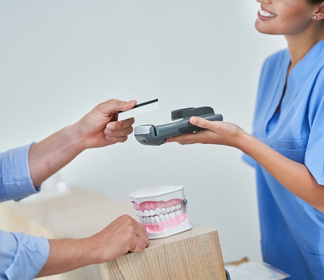 a patient paying for his tooth extraction in Dallas, TX