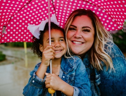 Smiling mother and daughter standing under an umbrella