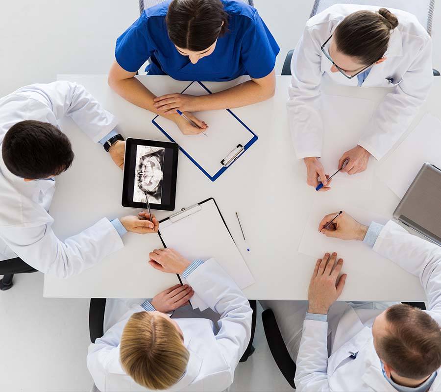 Dental team members sitting at table and looking at tablets and papers