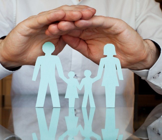 hands covering paper cut out family