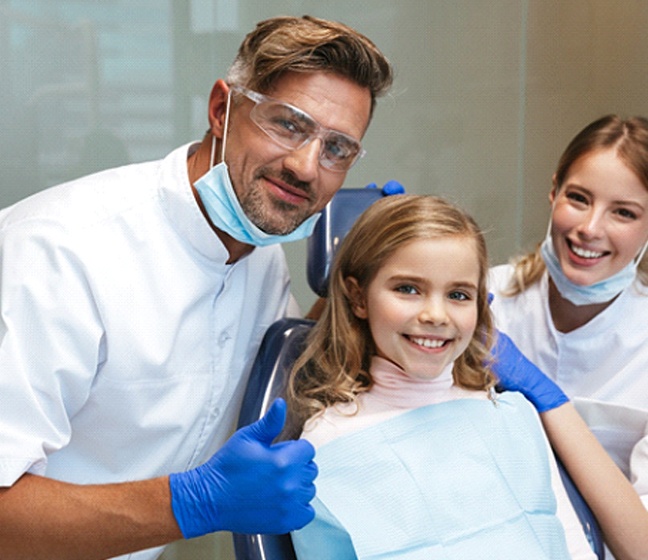 Girl smiling with dental team in Dallas