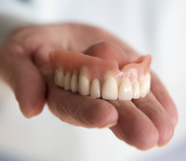 Hand holding a full denture