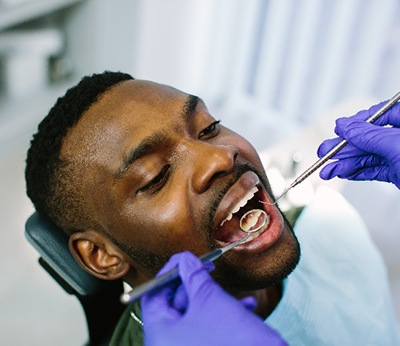 Dentist using tools to examine patient's teeth