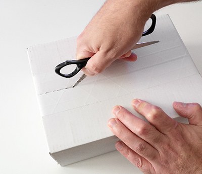 Man using scissors to open white box