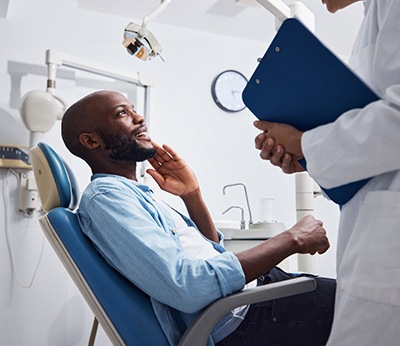 Smiling patient talking to dentist holding clipboard