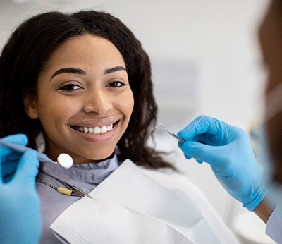 Woman smiling while dentist examines her teeth