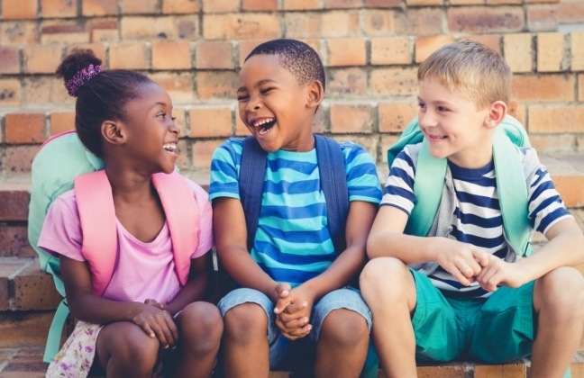 Three kids laughing together after children's dentistry visit