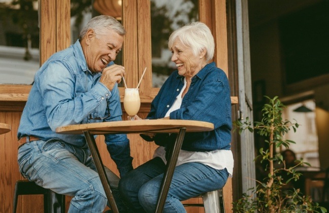 Older man and woman laughing together after replacing missing teeth