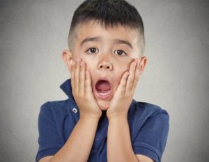 child covering his mouth in shock over knocked out tooth