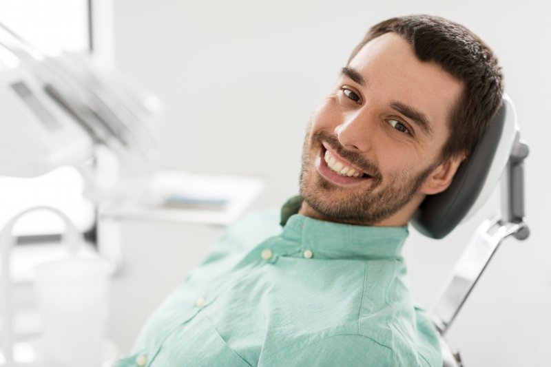 : A close-up of a smiling man sitting in a dentist’s chair