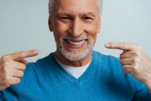 Man smiling and pointing at his dentures